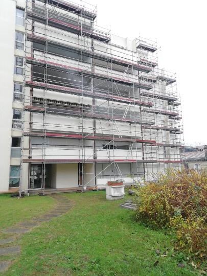 Des échafaudages entourent un immeuble de grande hauteur en rénovation