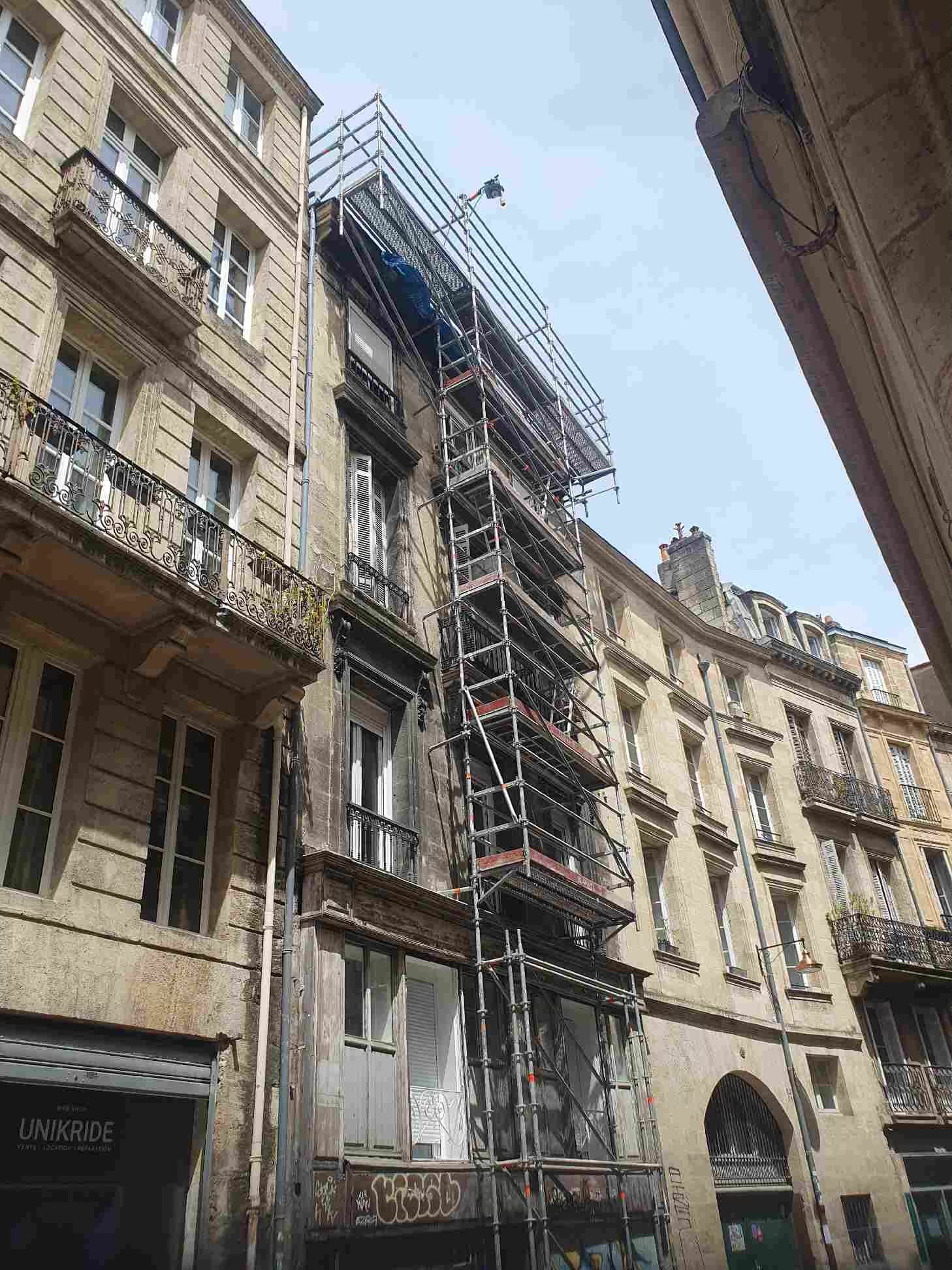 Des échafaudages recouvrent la façade d'un immeuble de plusieurs étages