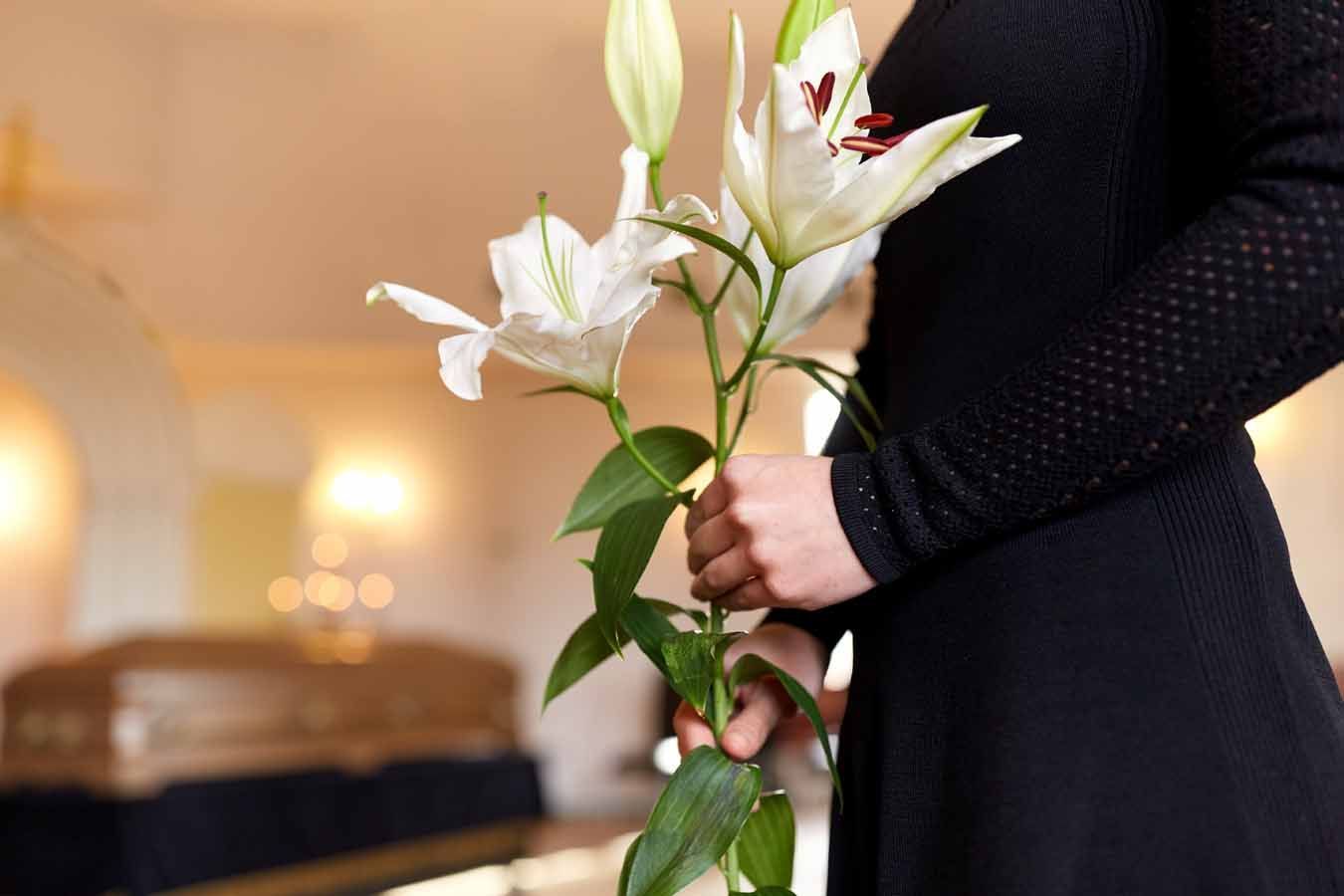 Homme tenant des fleurs devant un cercueil
