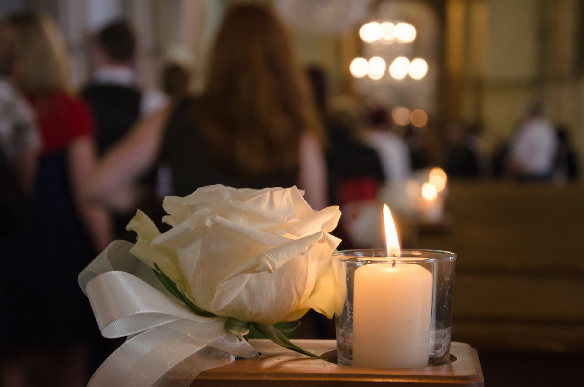 Rose et bougie allumée posées sur un banc d'église