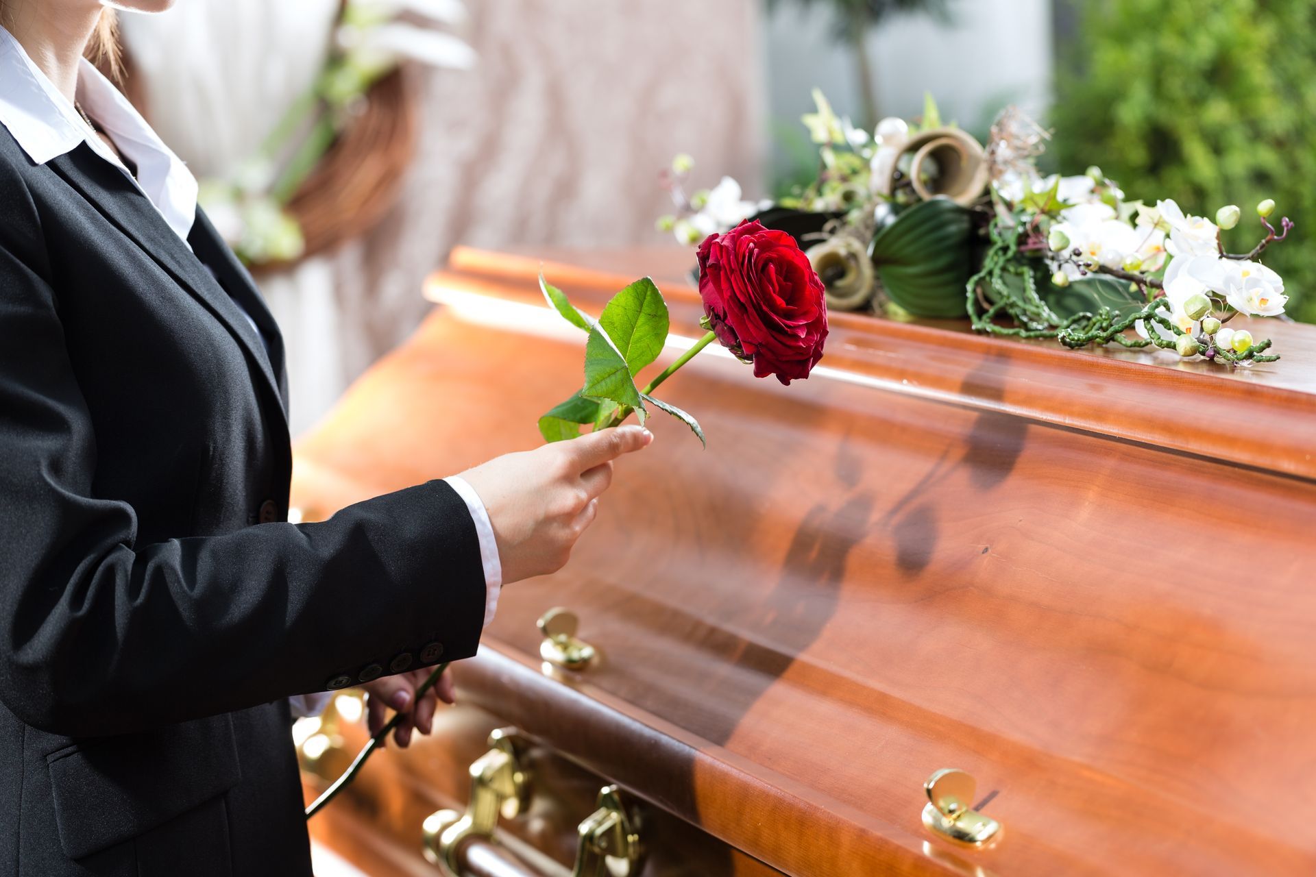 Personne posant une rose rouge sur un cercueil