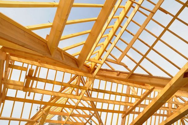 Charpente de toit en bois en construction sur fond de ciel lumineux