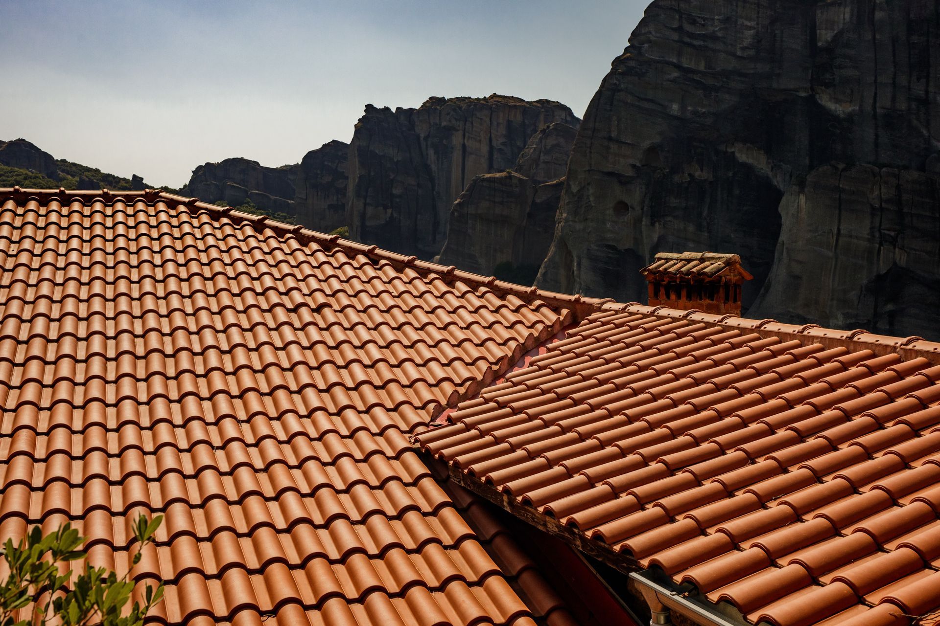 Toits de tuiles rouges devant de sombres falaises rocheuses sous un ciel clair