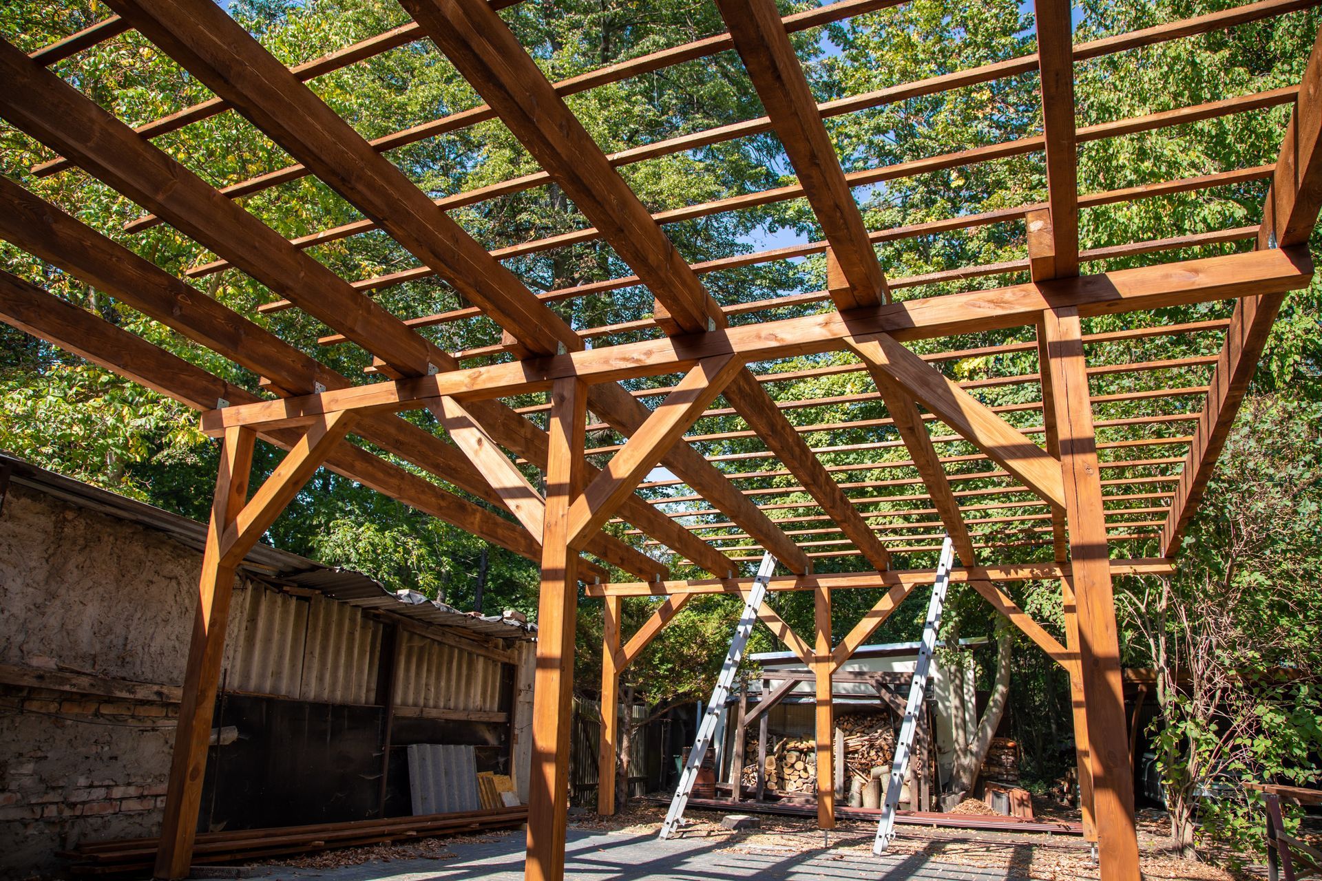 Pergola en bois avec toit en treillis au-dessus d'un chemin de jardin extérieur, arbres en arrière-plan