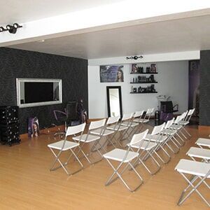 Interior de uma sala preparada para uma apresentação. Cadeiras dobráveis ​​brancas estão posicionadas de frente para espelho.