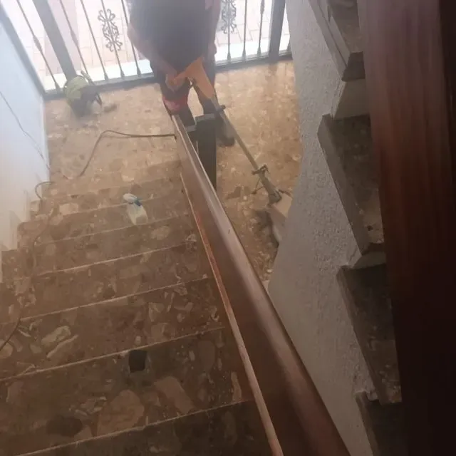 Una persona está parada en un tramo de escaleras sosteniendo una herramienta.