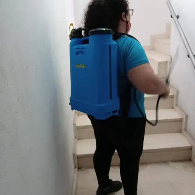 Una mujer que lleva una mochila pulverizadora azul baja las escaleras.
