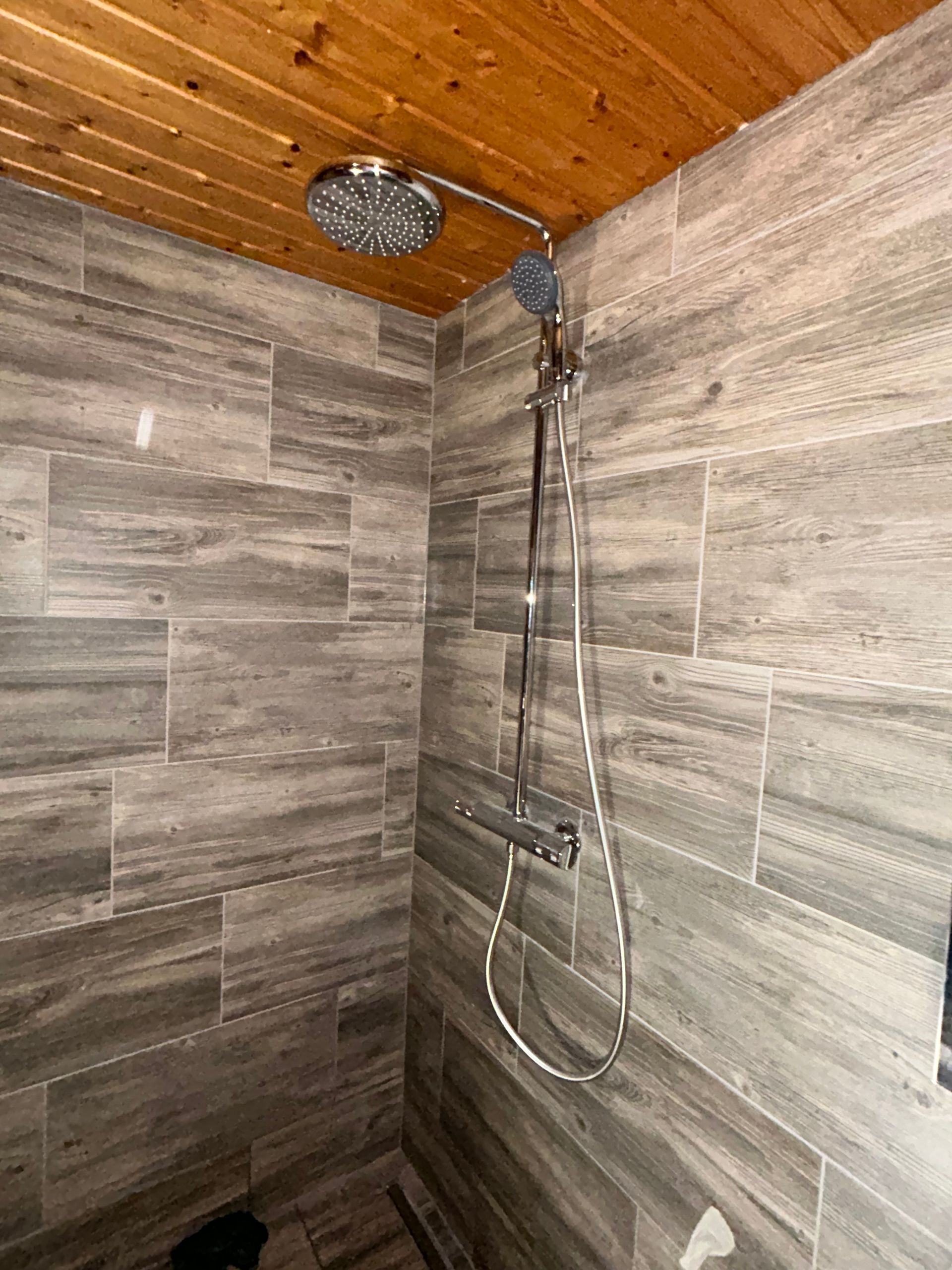 Eine Dusche mit Holzdecke und Duschkopf.