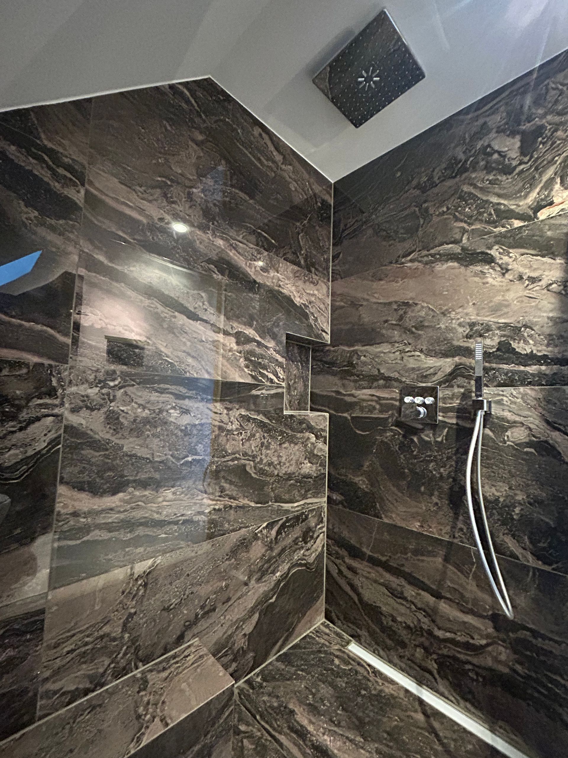 Ein Badezimmer mit ebenerdiger Dusche und Marmorwand.