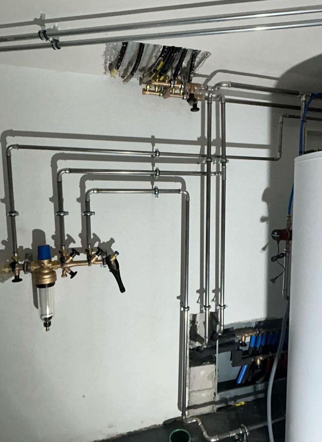 Ein Raum mit vielen Rohren und einem Warmwasserbereiter.