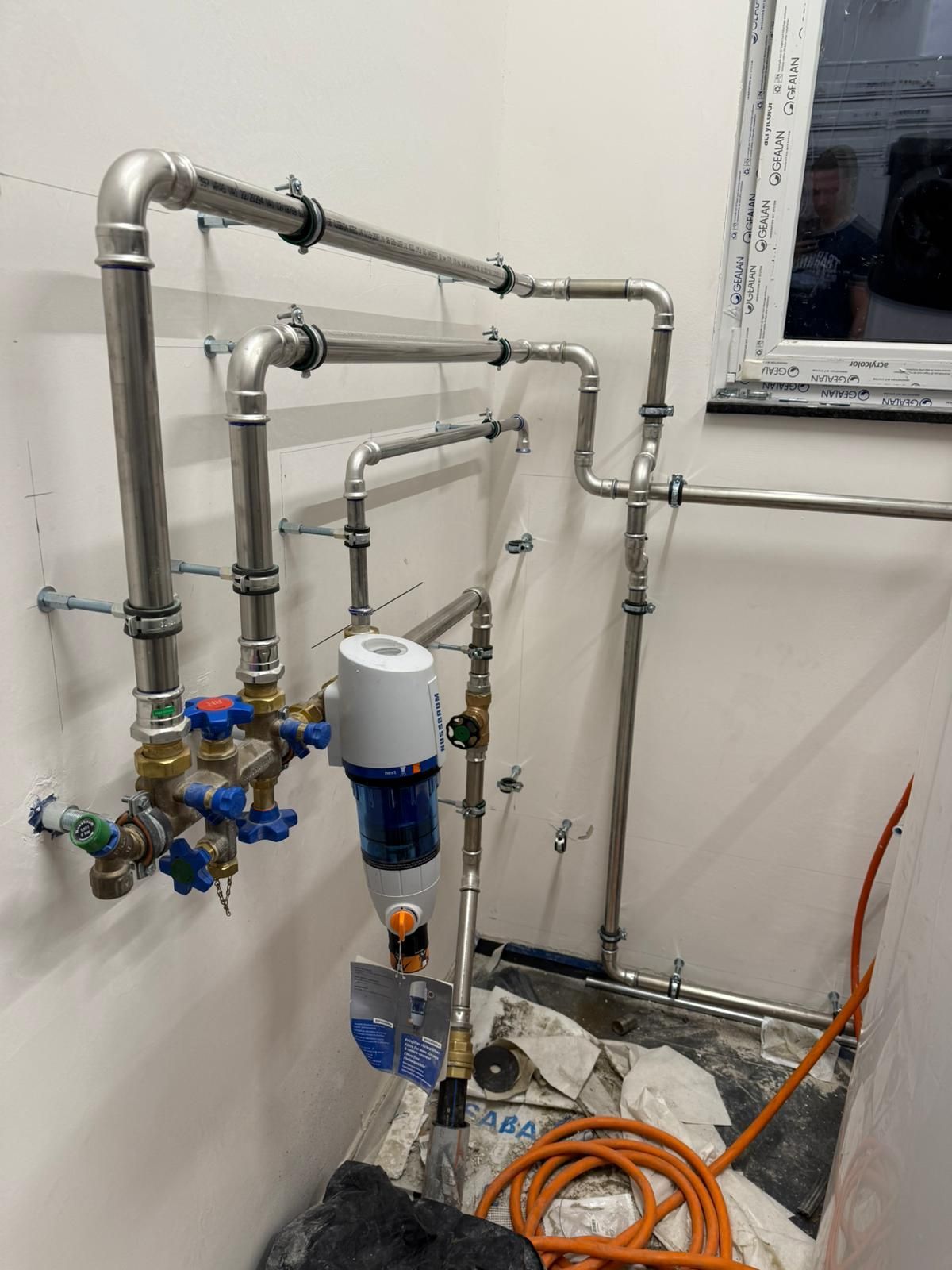 Ein Badezimmer mit vielen Rohren und einem Fenster.