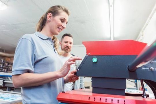 Un hombre y una mujer están trabajando en una máquina en una fábrica.