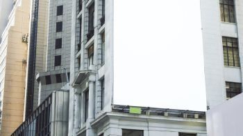 Un gran cartel blanco cuelga del costado de un edificio en una ciudad.
