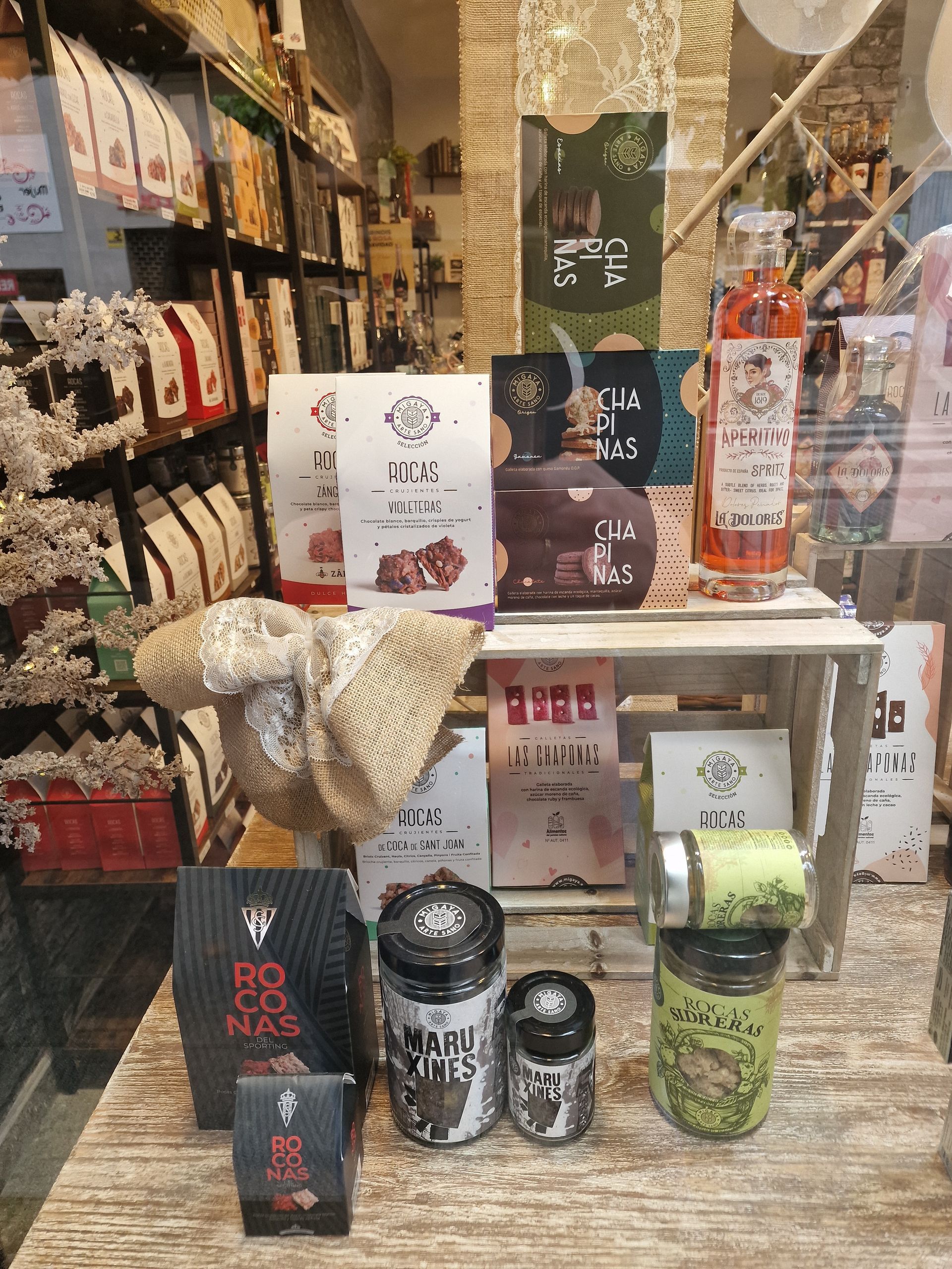 Exhibición de café y productos relacionados, principalmente de color marrón, blanco y verde. Estante de madera.