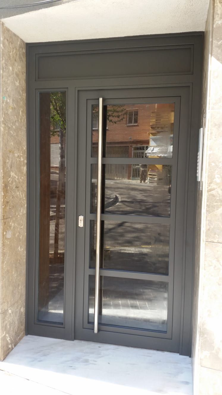 Una puerta negra con manija de acero inoxidable en un edificio.