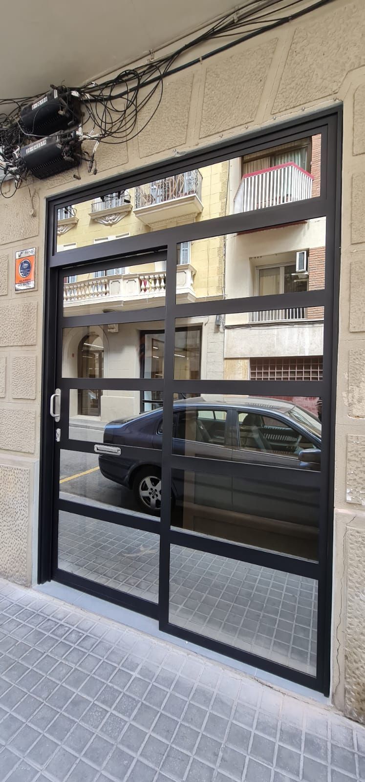 Un coche está aparcado delante de una puerta de cristal.