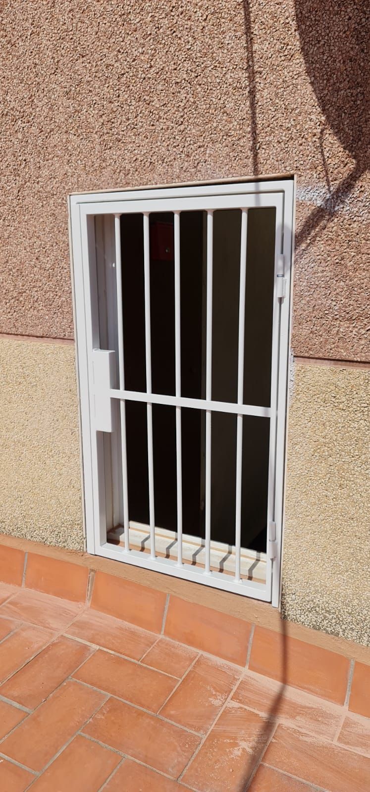 Una ventana con rejas está en el costado de un edificio.