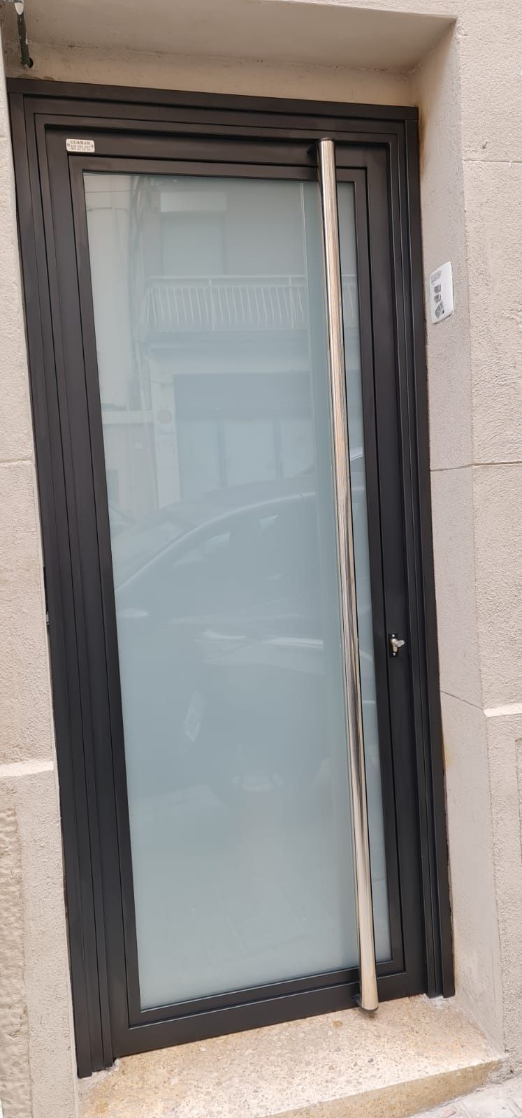 Una puerta con una puerta de vidrio y una manija de metal en un edificio.