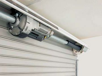 Un primer plano de un motor de puerta de garaje en una puerta de garaje.