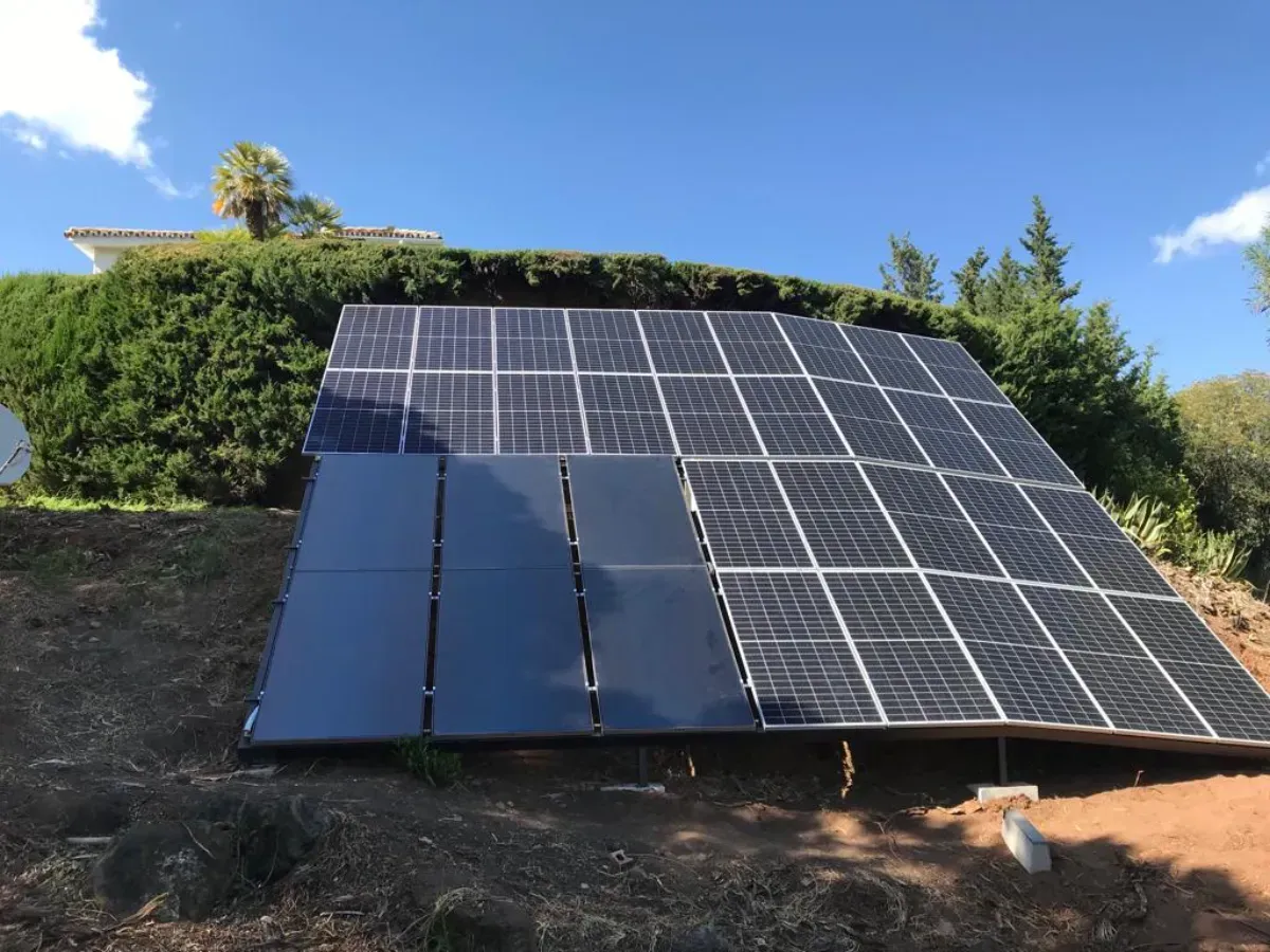 Un conjunto de paneles solares instalados en el suelo, con una combinación de paneles estándar de células azules y paneles