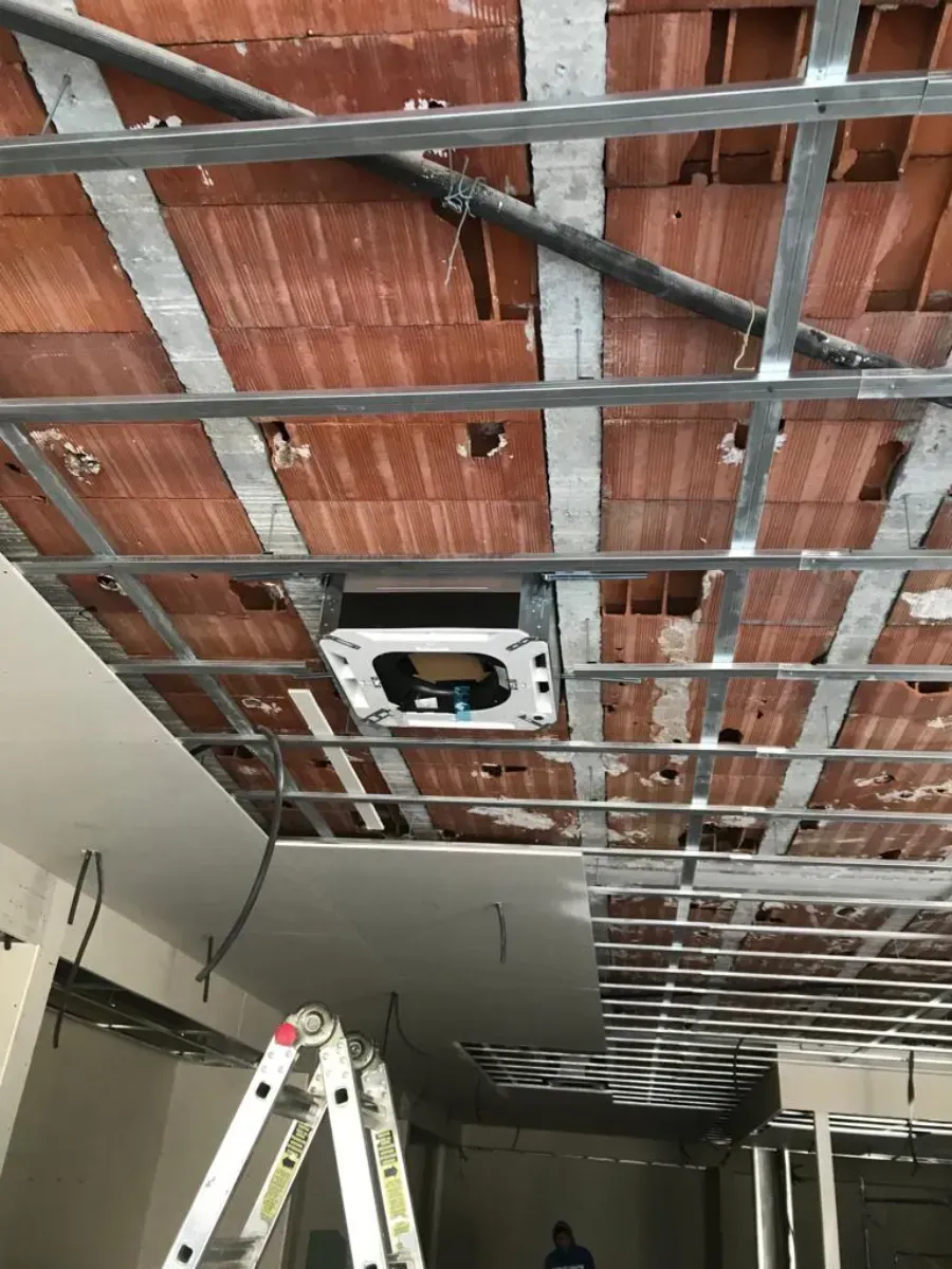 En el interior de la obra se puede ver la estructura del techo con rejilla metálica y la instalación de una unidad