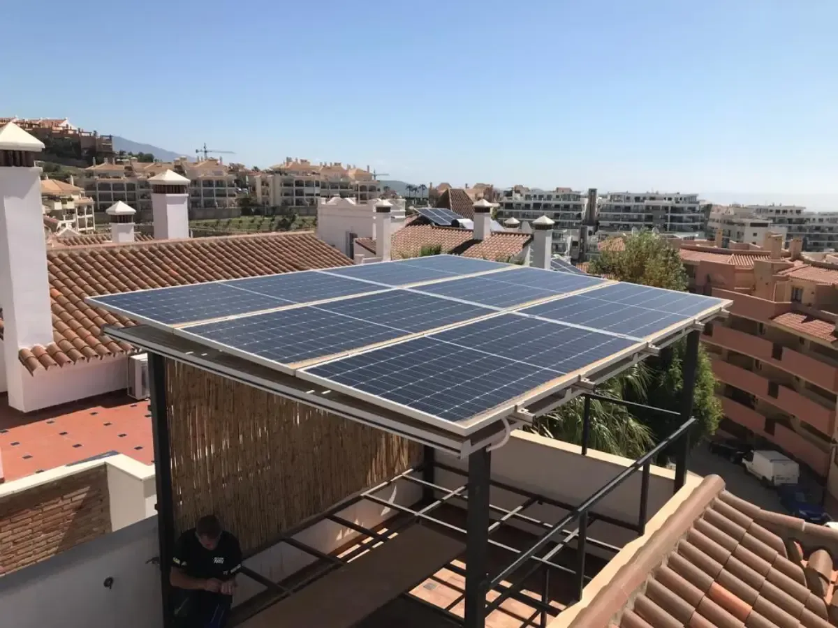 Una marquesina con paneles solares instalada en una terraza en la azotea con vistas a un pueblo costero