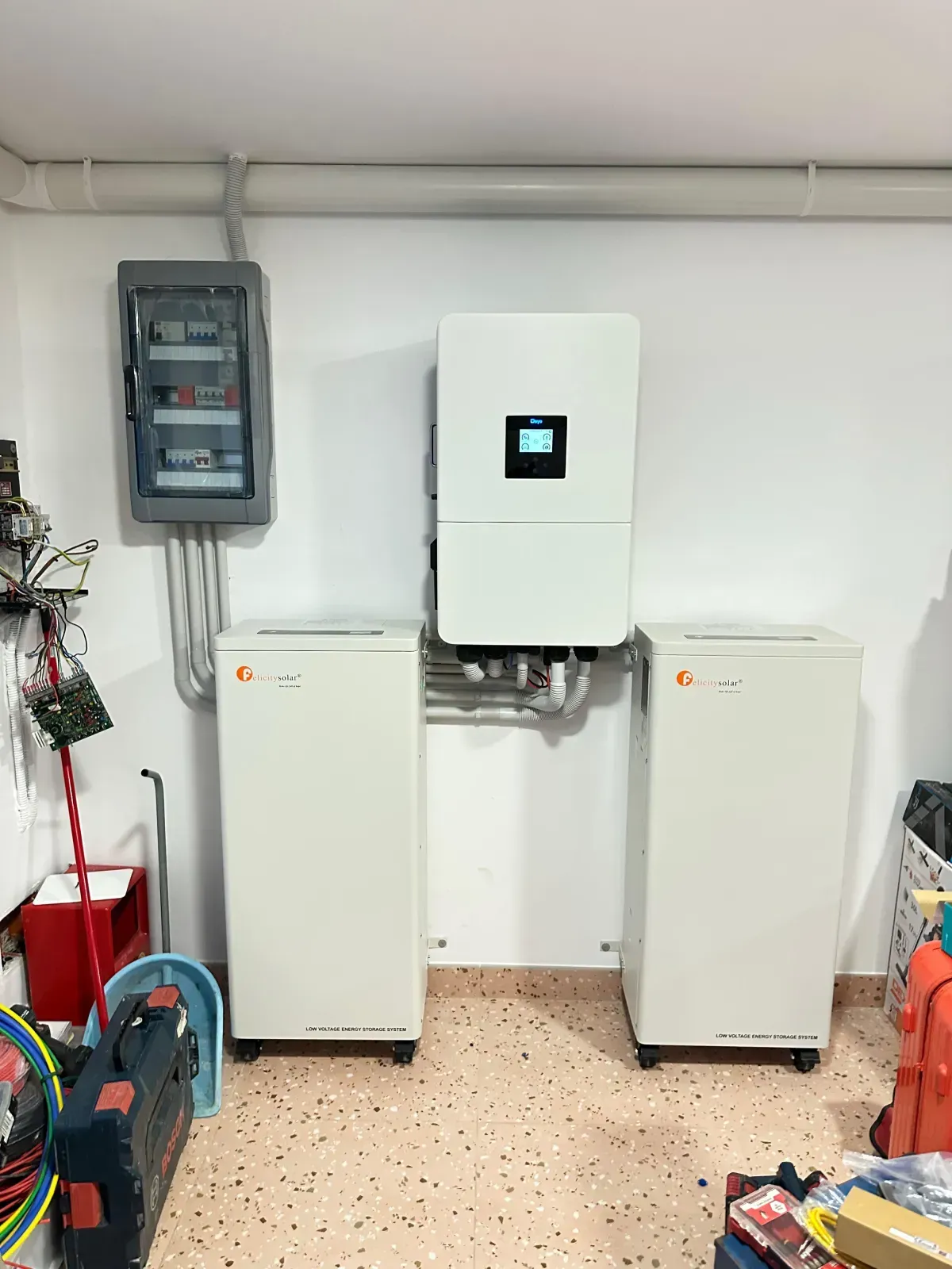 Un sistema doméstico de almacenamiento de energía solar con un inversor montado en la pared y dos unidades de baterías