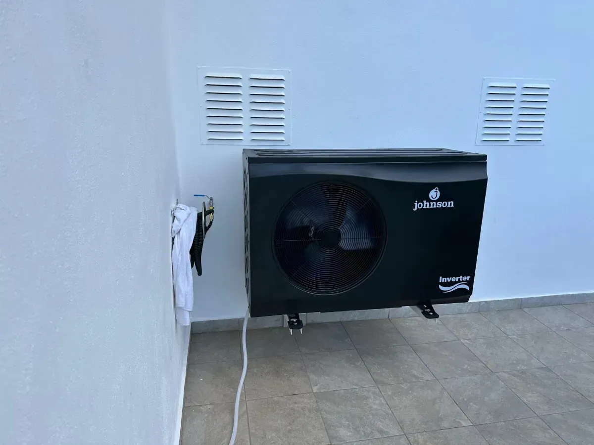 Un aparato de aire acondicionado negro montado en la pared, sobre una pared exterior blanca