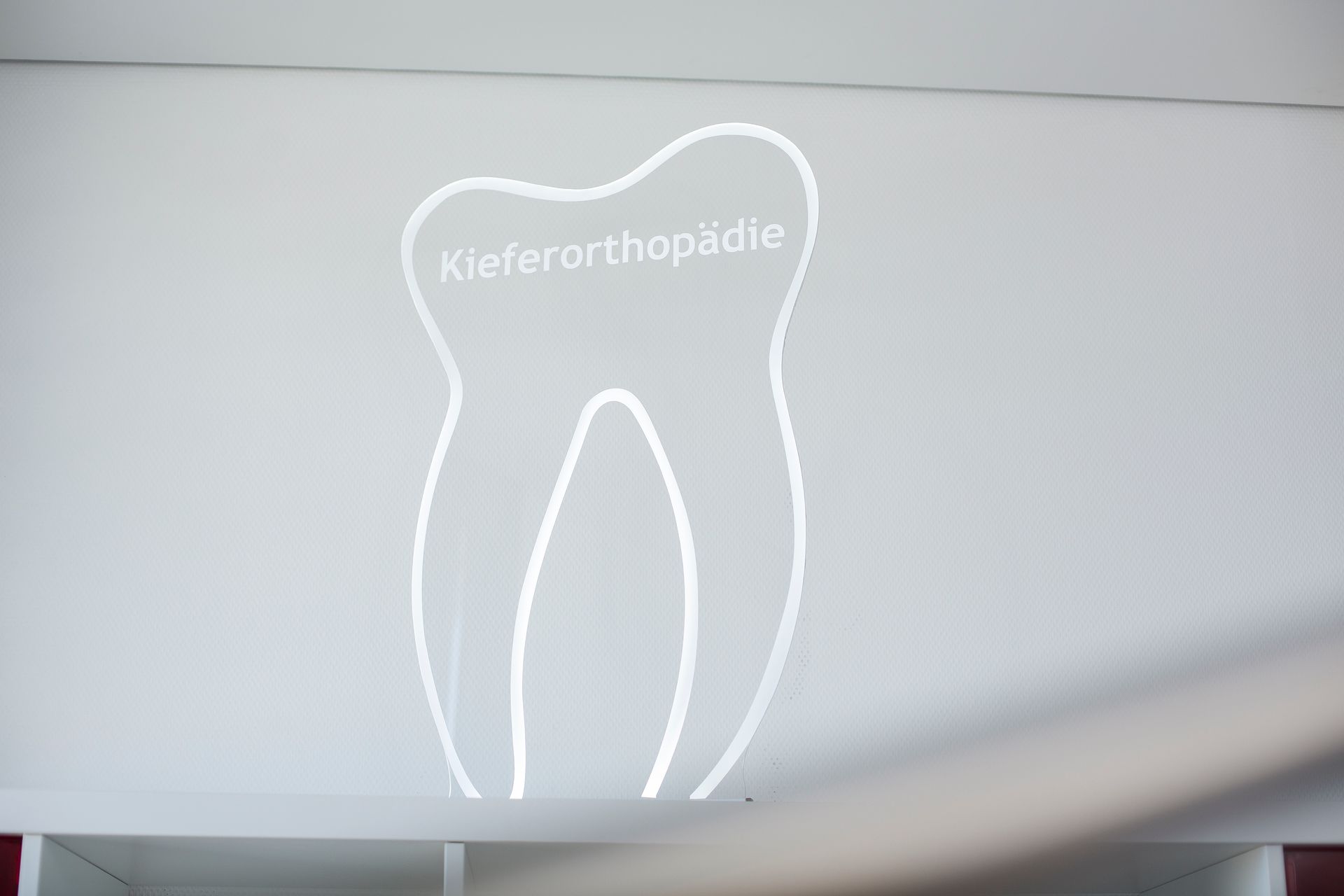 Auf eine weiße Wand in einer Zahnarztpraxis ist ein Zahn gezeichnet.