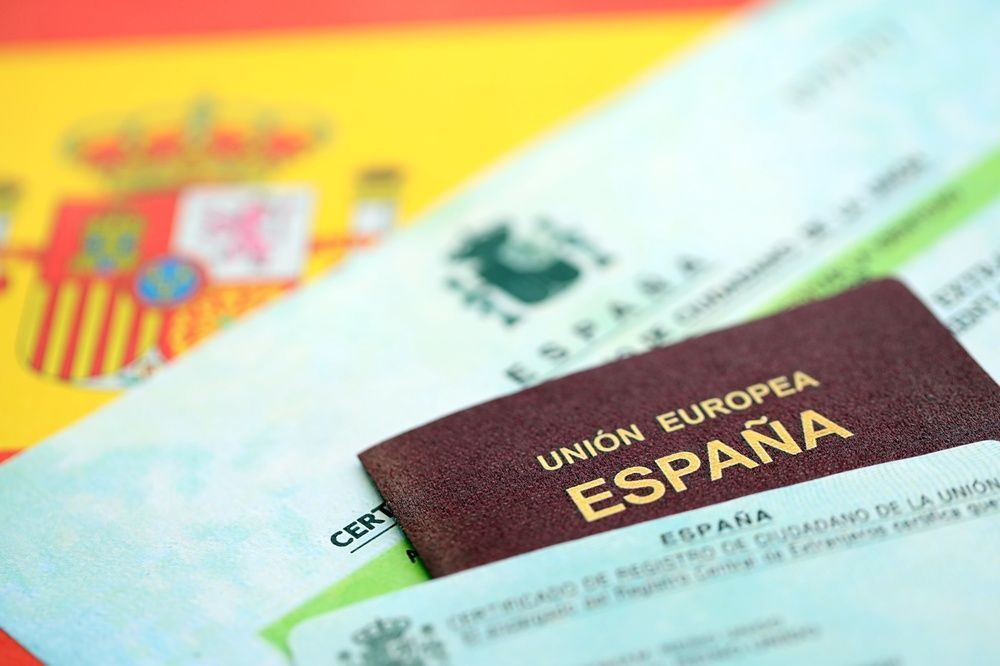 Pasaporte español y documentos oficiales, ocultando parcialmente una bandera española.