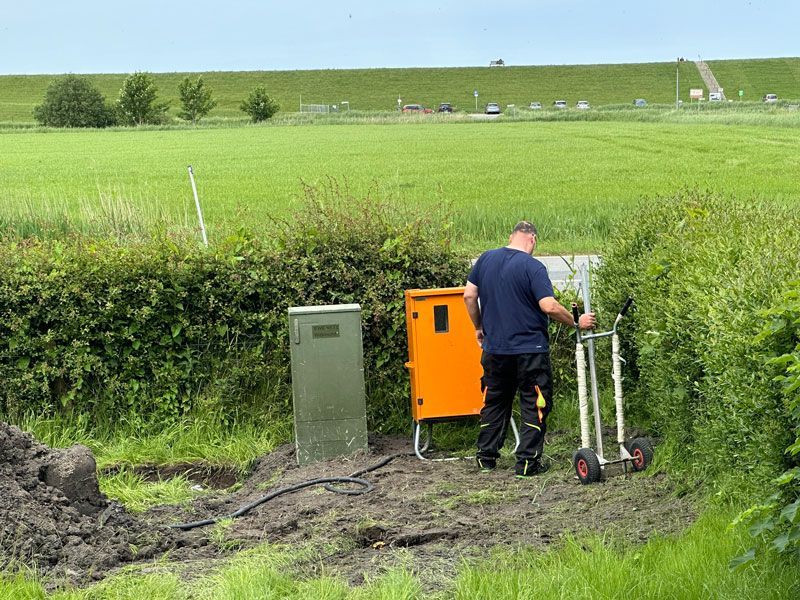 Ein Mann steht mit einem Karren mitten auf einem Feld.