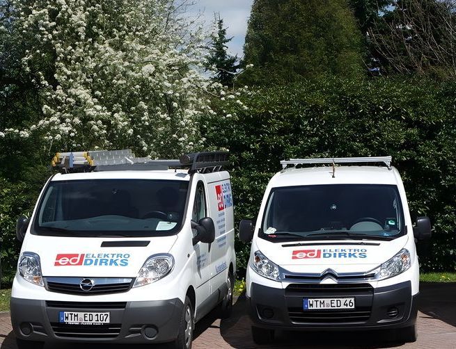 Auf einem Parkplatz stehen drei weiße Wagen von Dirks nebeneinander.