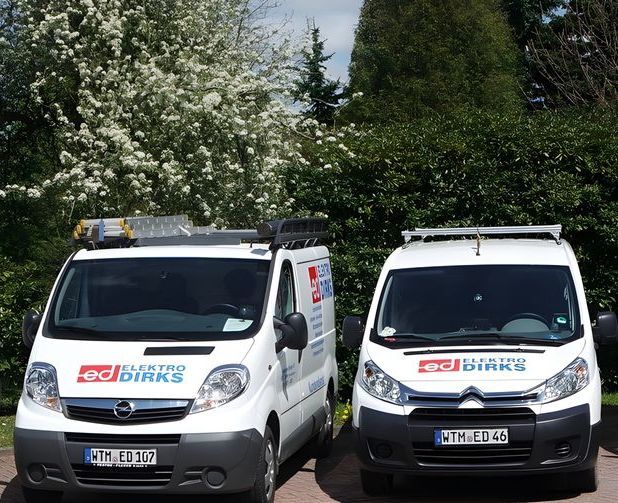 Auf einem Parkplatz stehen drei weiße Wagen von Dirks nebeneinander.