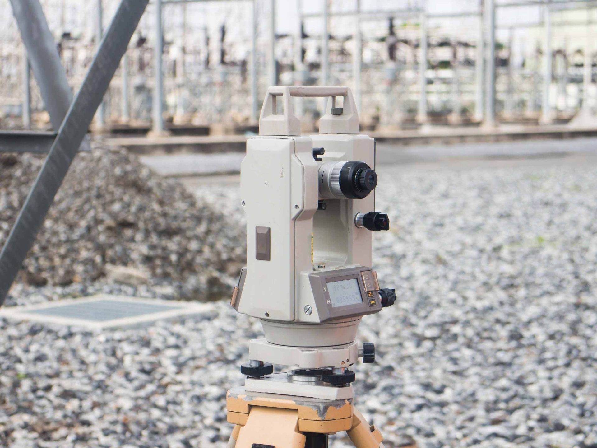 Un teodolito está colocado encima de un trípode en un camino de grava.