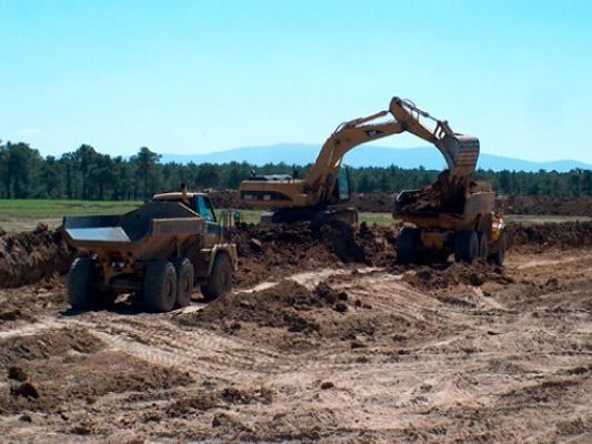 Un camión volquete está siendo cargado con tierra por una excavadora