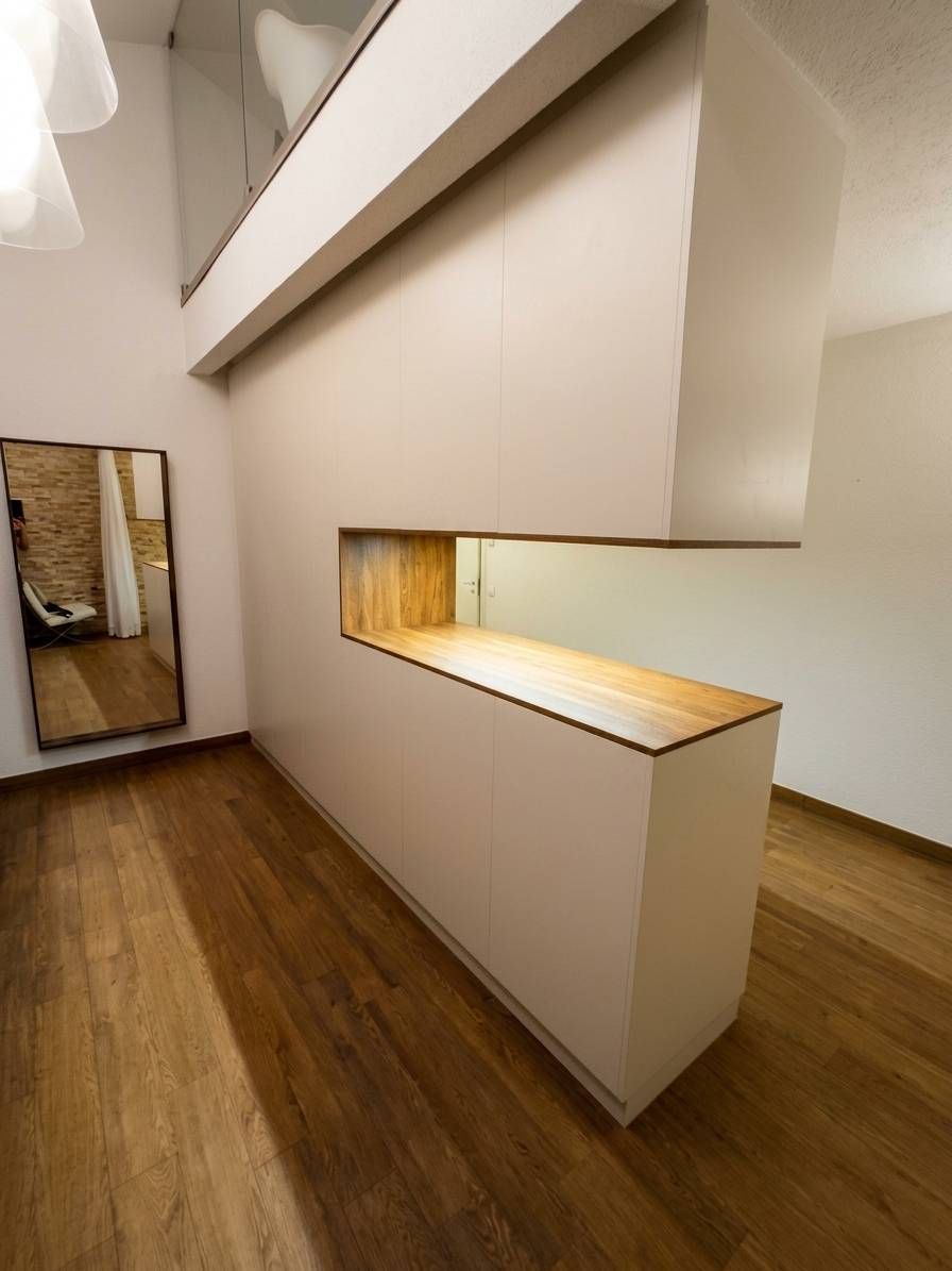 Corridoio moderno e minimalista con pavimento in legno, pareti bianche e un armadio a muro stretto e illuminato.