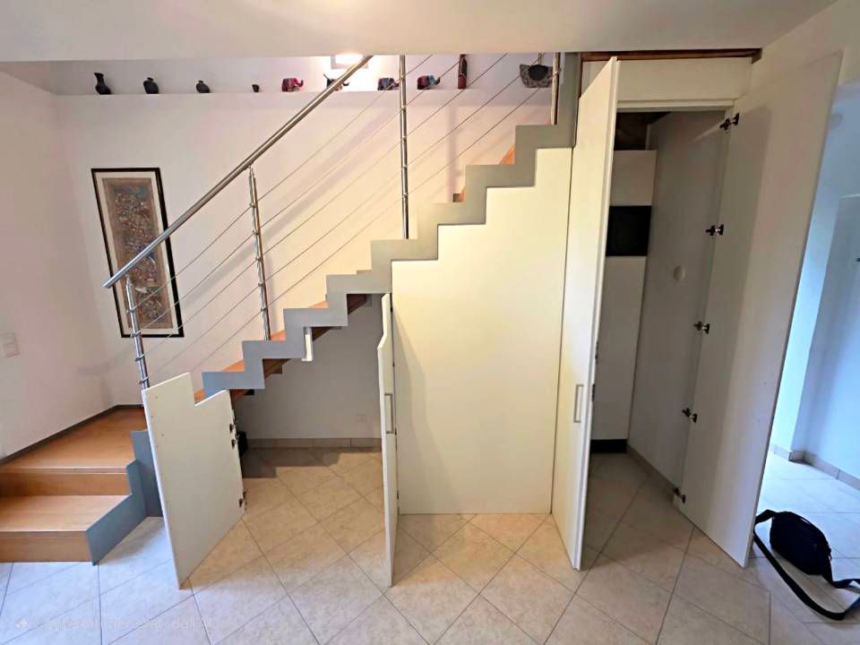 Interno moderno con scala, ringhiera in cavo e porta in una stanza bianca
