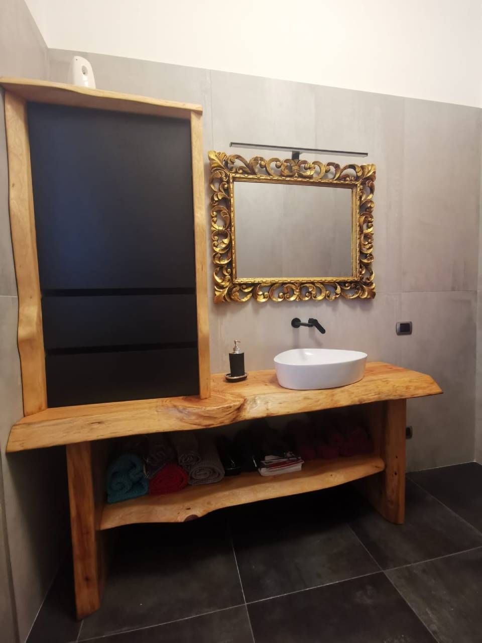 Mobiletto da bagno rustico in legno con lavabo a ciotola bianco e specchio dorato decorato in un piccolo bagno