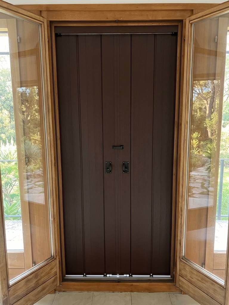 Doppia porta d'ingresso in legno con pannelli laterali in vetro e telaio in legno, vista dall'esterno.