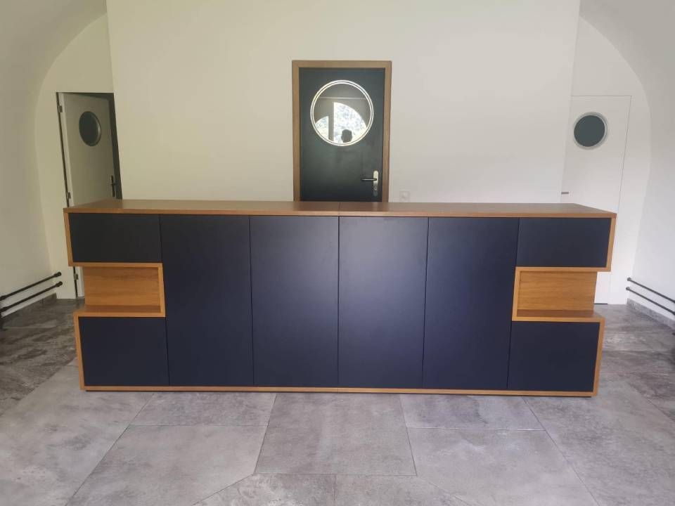 Mobile audio moderno con finiture in legno, pannelli scuri e orologio centrato su una parete bianca.