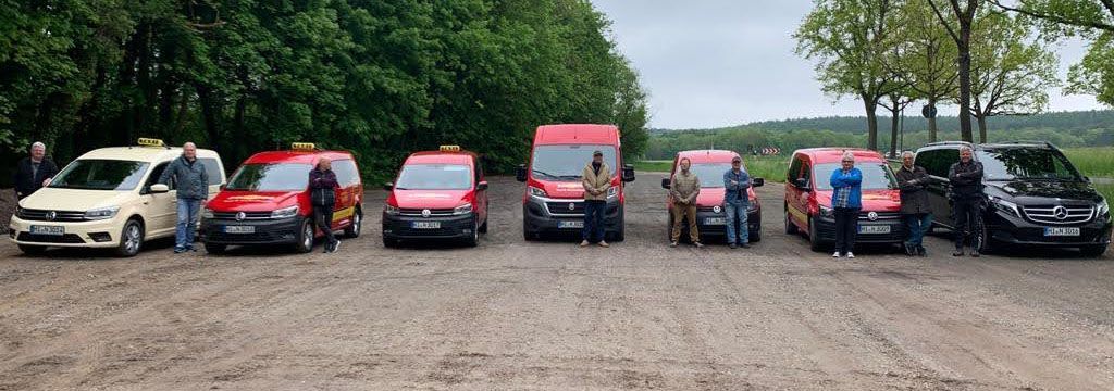 Eine Gruppe von Menschen steht vor einer Reihe roter Lieferwagen.