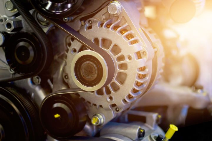Gros plan sur l'alternateur d'un moteur de voiture avec sa courroie.