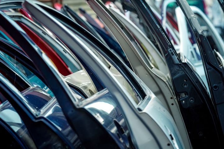 Des portières de voitures de différentes couleurs alignées dans un entrepôt de pièces automobiles.