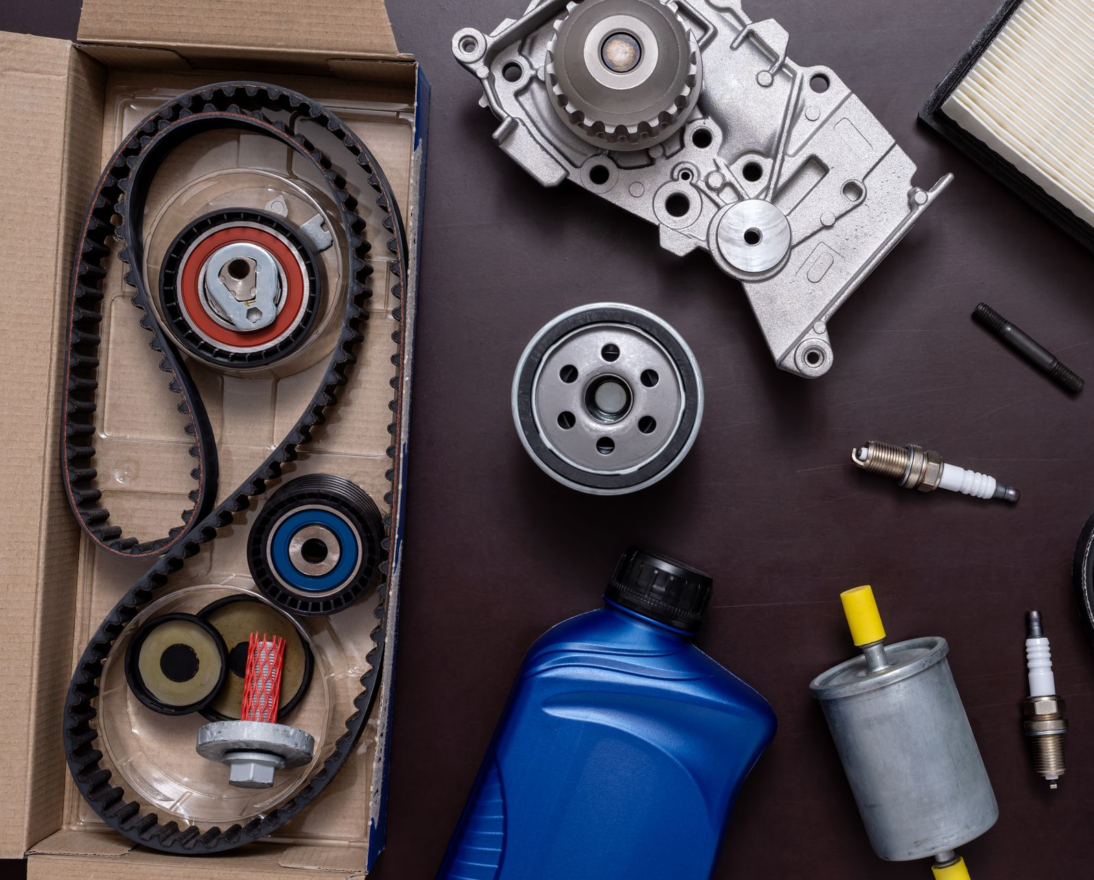 Des pièces automobiles, notamment un kit de courroie de distribution, un filtre à huile et un bidon d'huile.