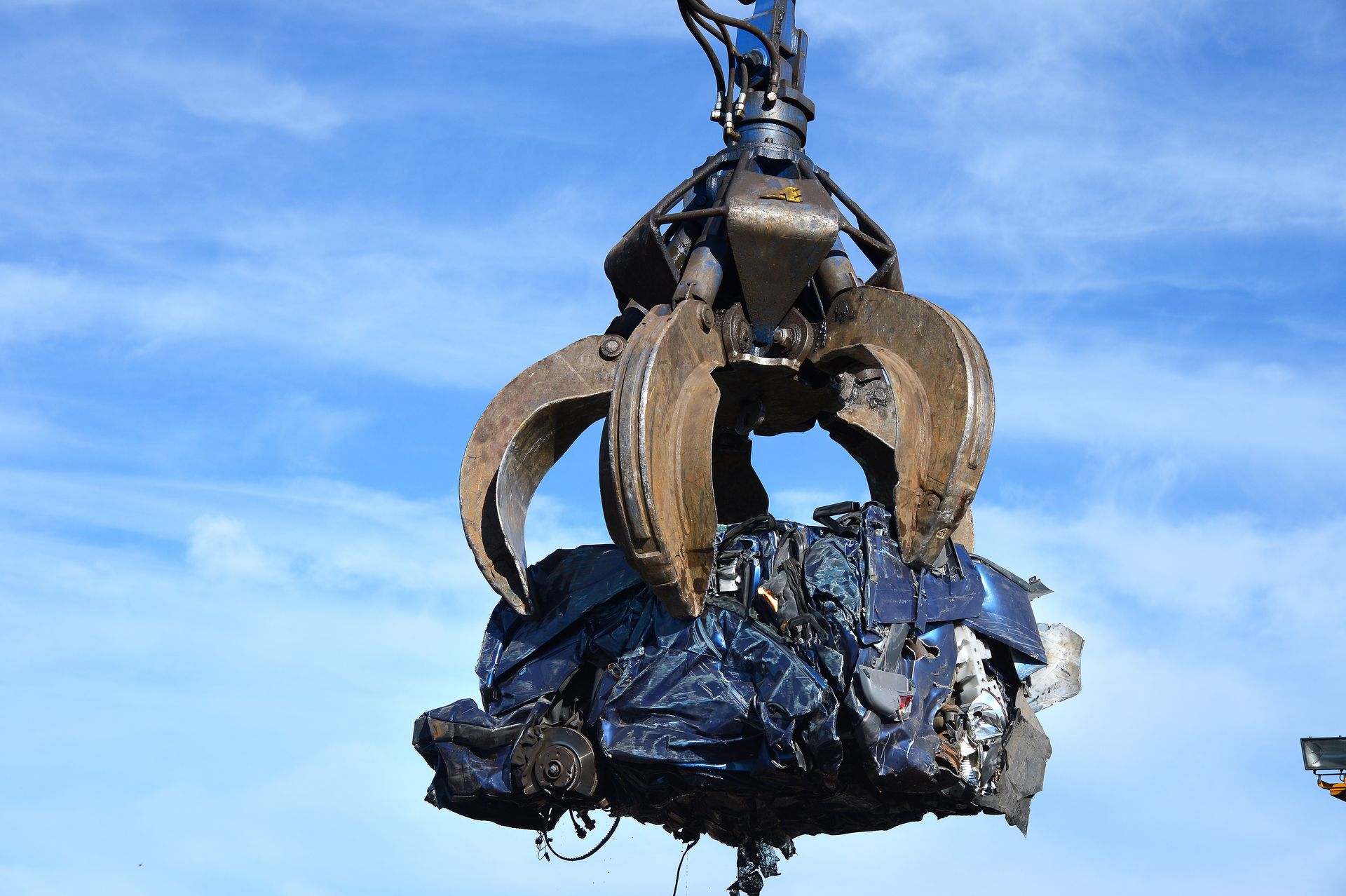 Une pince soulève une voiture écrasée.