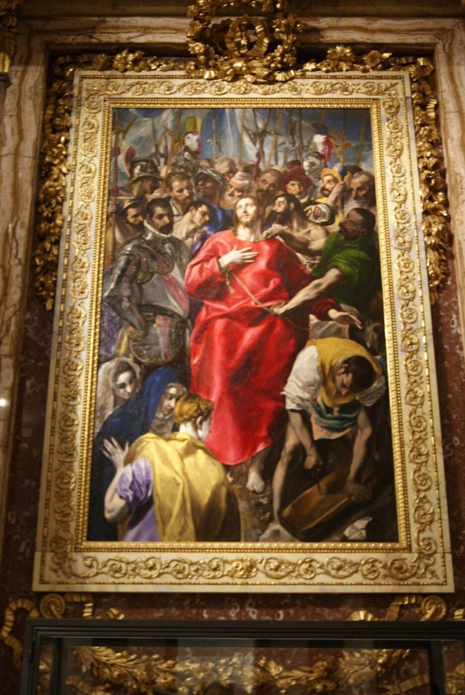 Cuadro de Cristo con túnica roja rodeado de gente; marco dorado ornamentado, ambientación interior.