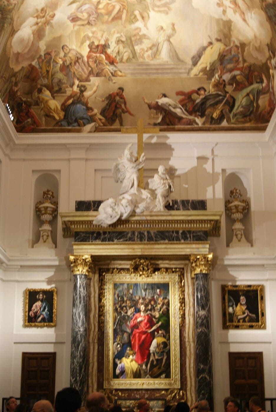 Interior de capilla ornamentado con fresco en el techo, pintura central y escultura.