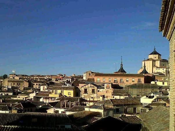 Vista de Toledo, España, con edificios antiguos, techos de tejas y un cielo azul claro.
