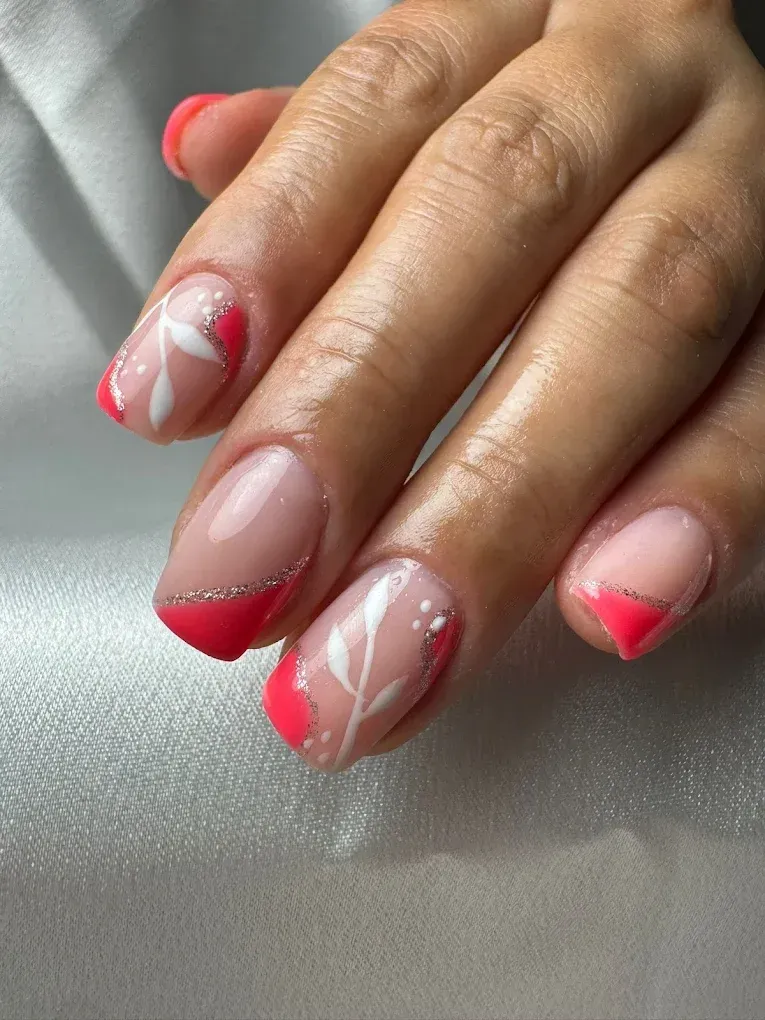 Primer plano de uñas cuidadas con diseños florales rosas y blancos sobre una base rosa.