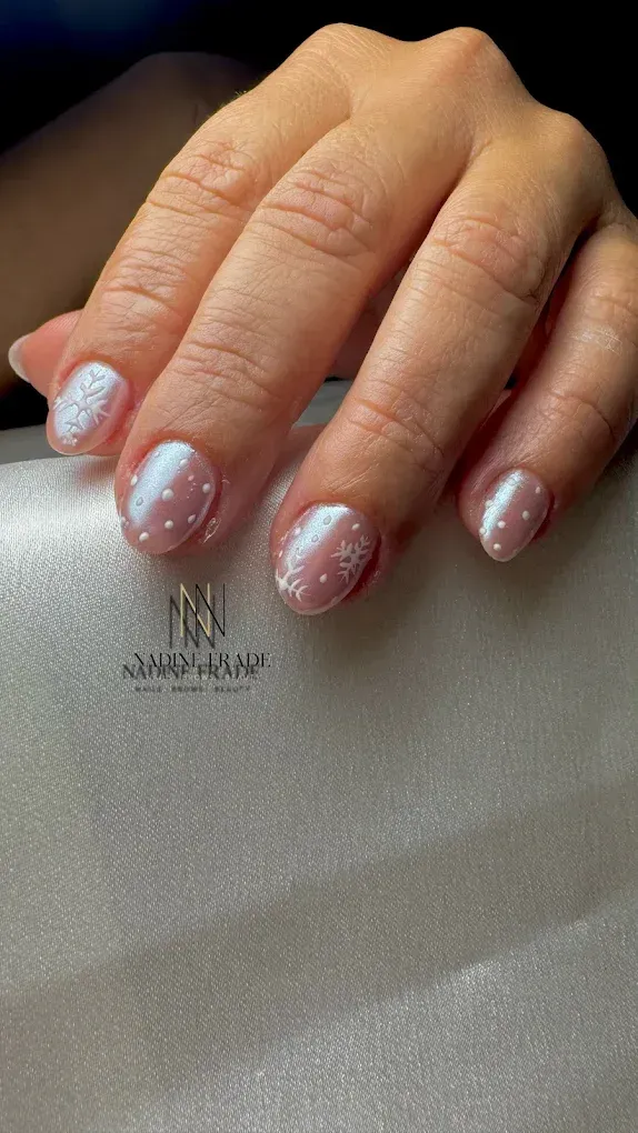 Mano cuidada con uñas de color rosa claro, algunas con detalles en brillo blanco.